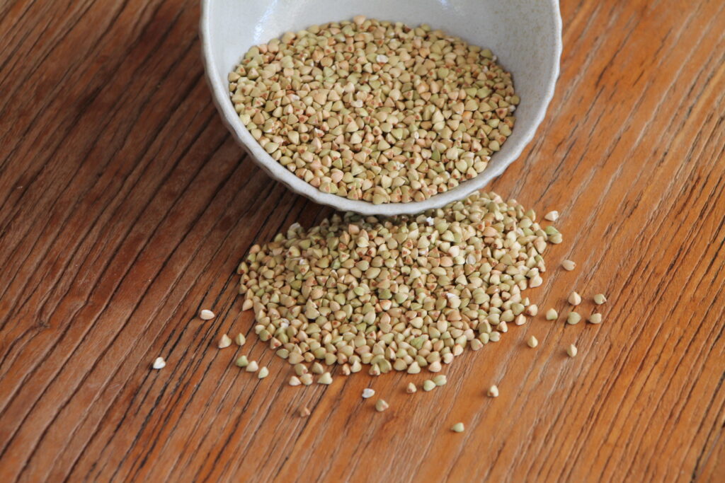 Buckwheat groats coming out of a bowl onto wooden table