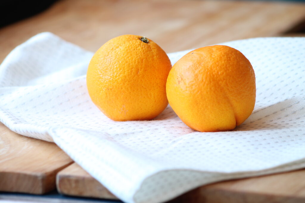 two oranges sitting on a tea towel